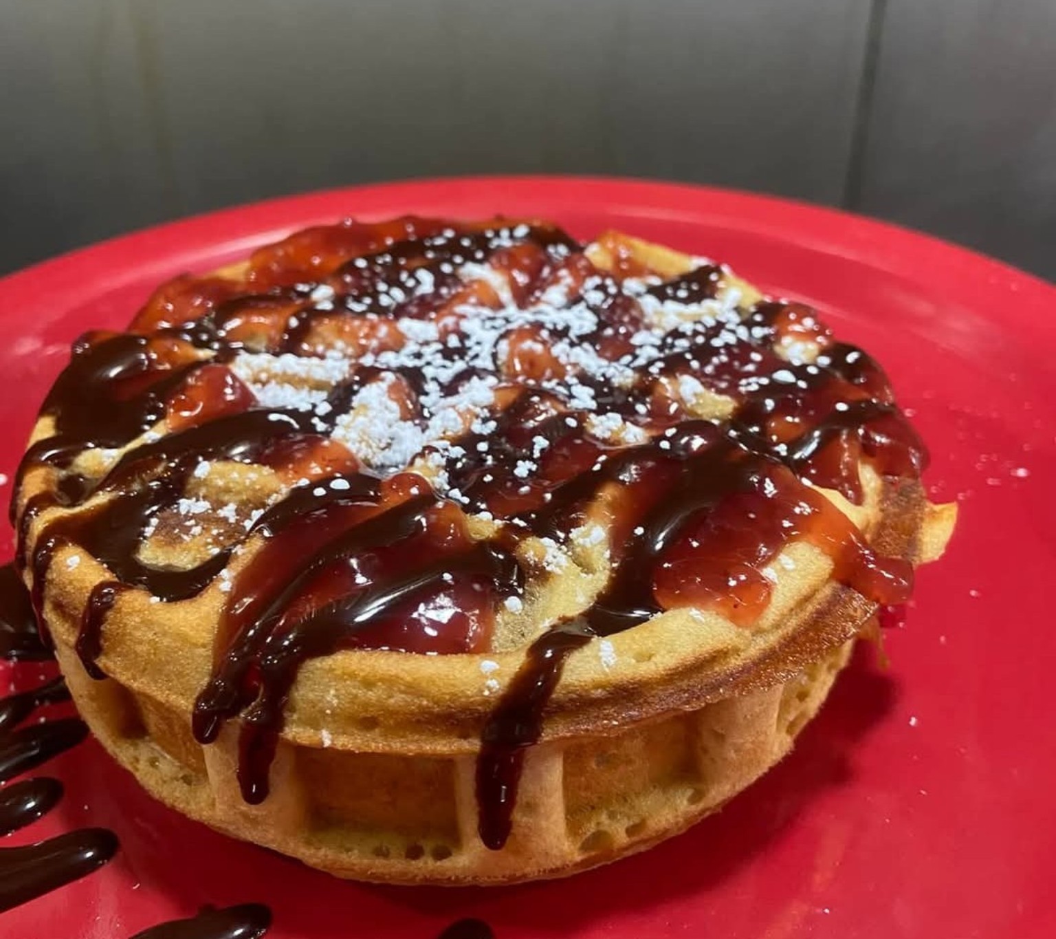 Golden waffle with berry topping and powdered sugar