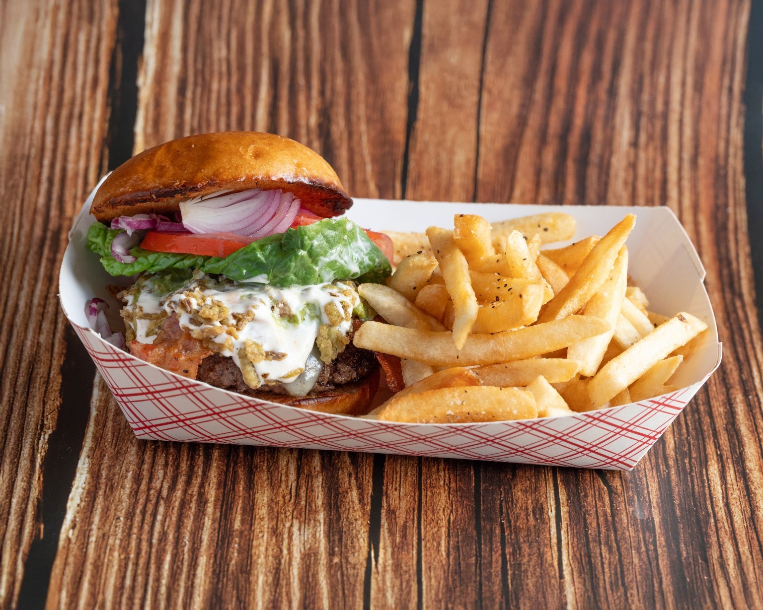 A Jesse James Foods burger piled with toppings, served beside golden fries