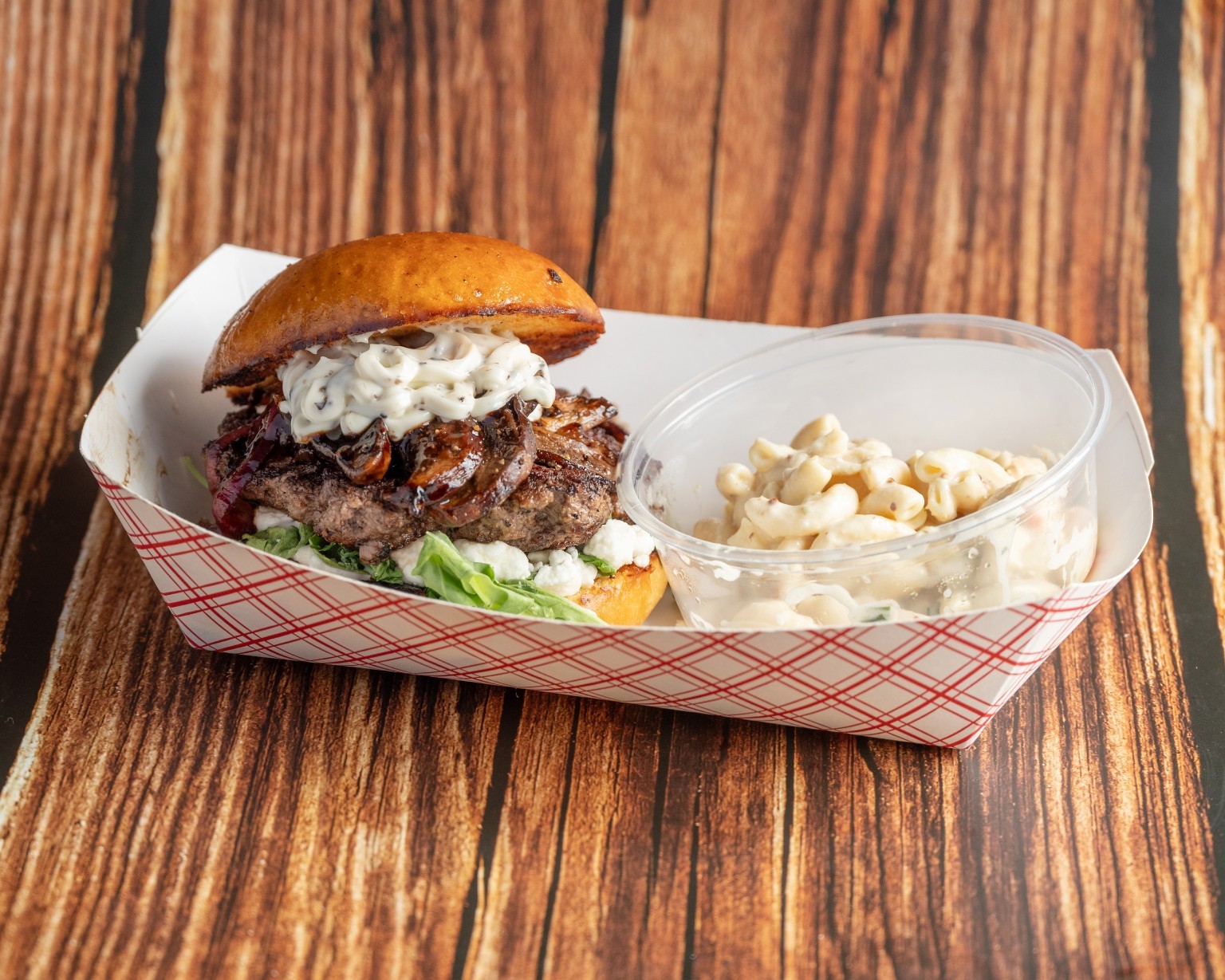 A burger topped with creamy sauce, served with a side